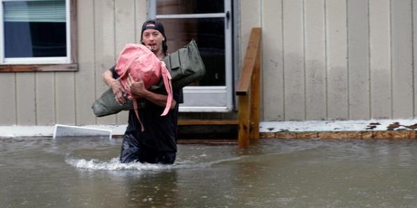 A man carries belo<em></em>ngings through floodwaters